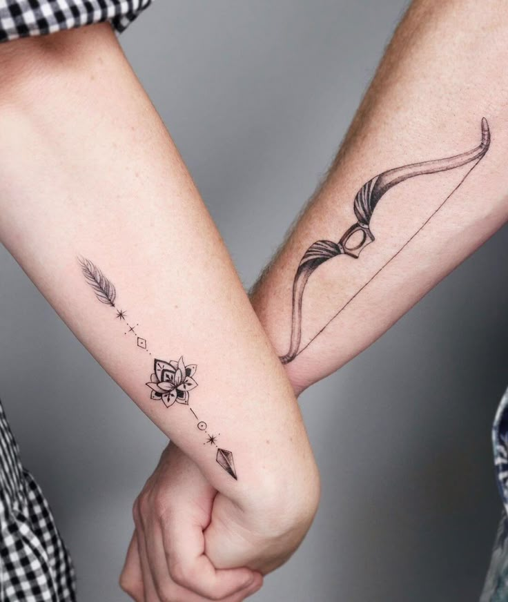 two people holding hands with tattoos on their arms