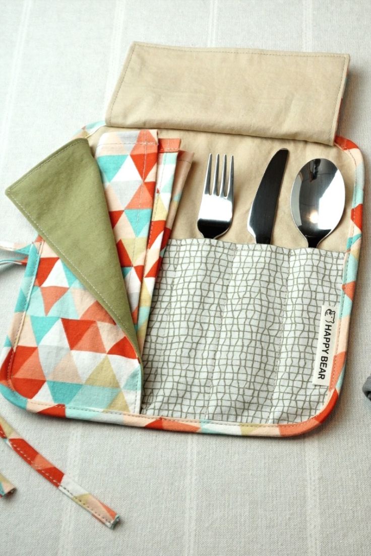 an assortment of utensils and spoons in a pouch on a tablecloth