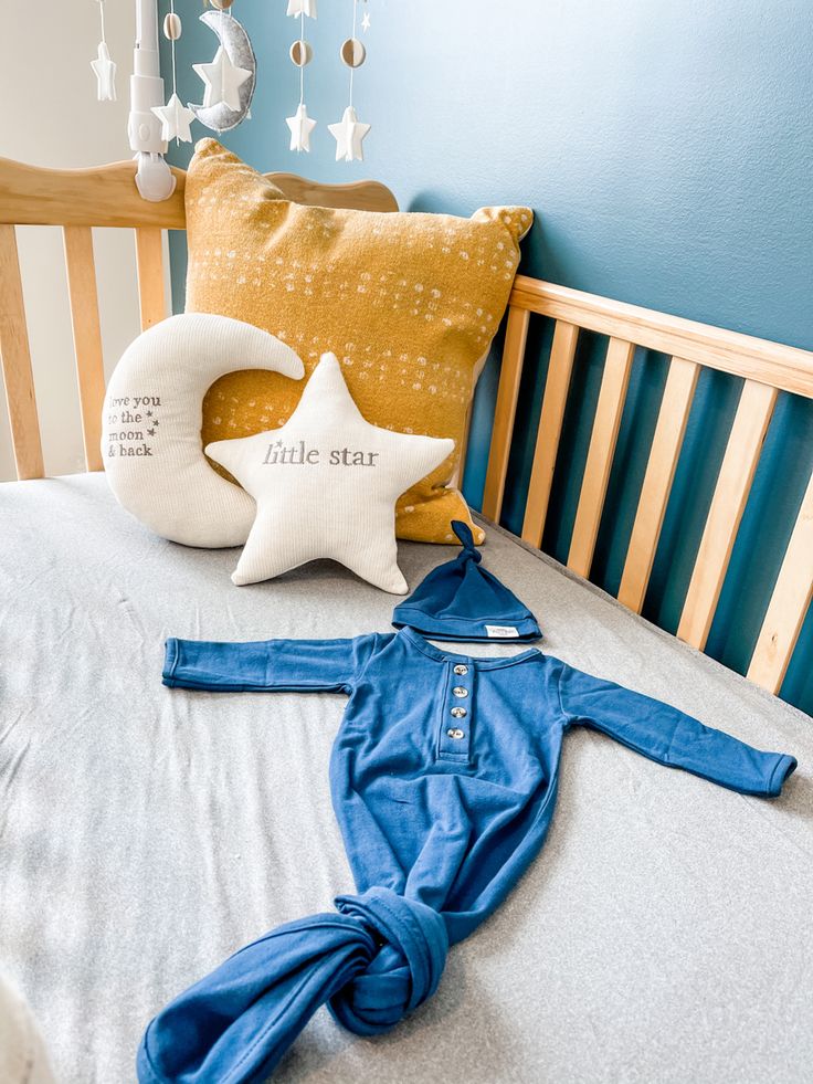 a baby's bodysuit laying on top of a bed next to a pillow