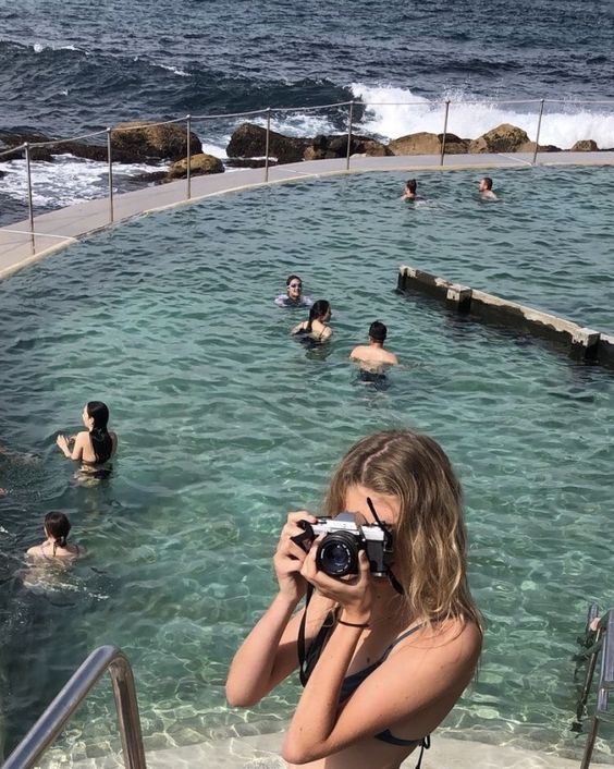 a woman taking a photo of people in the water