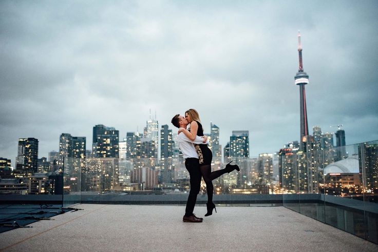 a man and woman kissing in front of a city skyline