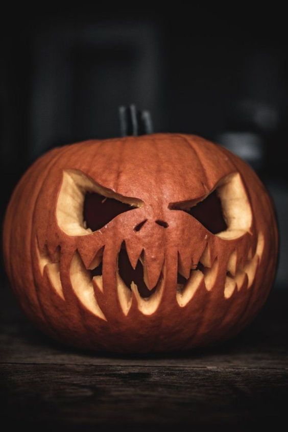 a carved pumpkin with teeth and fangs on it's face, sitting on a table