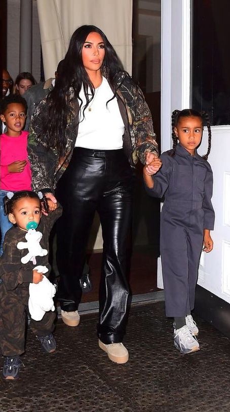 kim kardash and her children are walking out of the house with each other