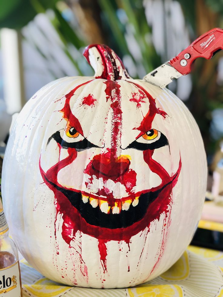 a painted pumpkin with a knife sticking out of it's mouth and blood splattered on the face