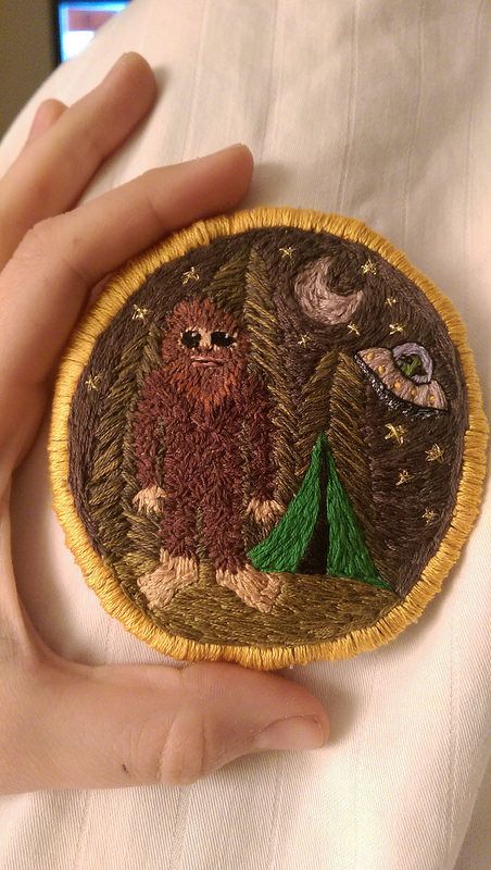 a person is holding an embroidered badge in their left hand and there are two owls on it