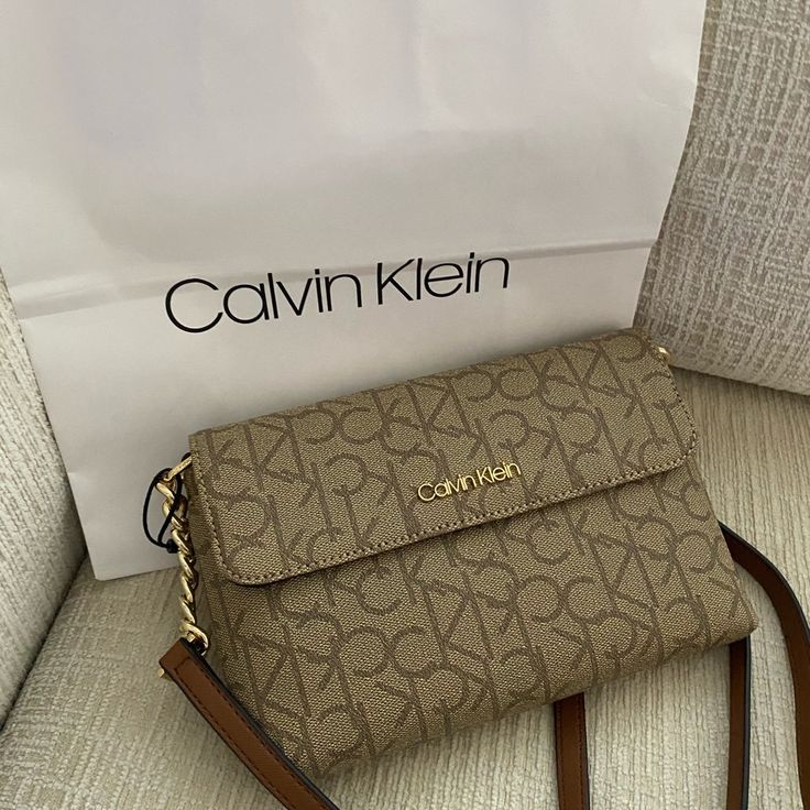 - Authentic Ck Handbag - Mini Sized Bag; 6-1/2"W X 7-1/2"H X 1-1/4"D (Width Is Measured Across The Bottom Of Handbag); 0.5 Lbs. Approx. Weight - 22"L Adjustable Strap - Zip Closure - Gold-Tone Exterior Hardware & 1 Slip Pocket With Magnetic Snap Closure - 1 Interior Slip Pocket & 2 Zip Pockets - Fits Iphone Xs Max Or Smaller Model Brown Flap Bags With Branded Hardware, Everyday Rectangular Calvin Klein Shoulder Bag, Calvin Klein Rectangular Shoulder Bag For Daily Use, Calvin Klein Rectangular Bag For Everyday, Beige Flap Shoulder Bag With Branded Hardware, Classic Calvin Klein Top Handle Bags, Daily Use Flap Bag With Branded Hardware, Brown Flap Bag For Shopping, Calvin Klein Classic Shoulder Bag