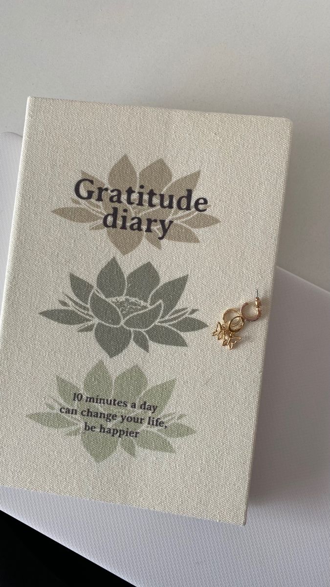 a greeting card with the words, gratitude diary written on it and a gold flower charm