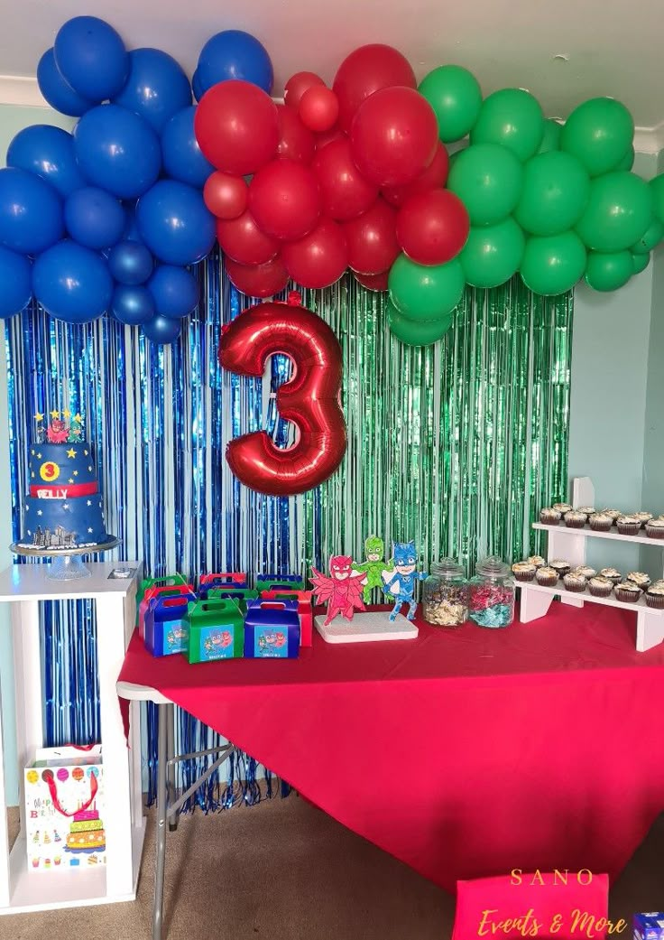 the table is covered with red, green and blue balloons that spell out the number three