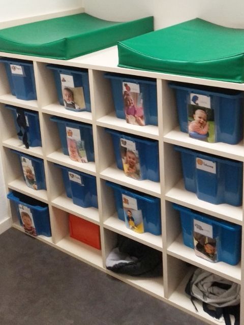 two white shelves filled with blue and green bins