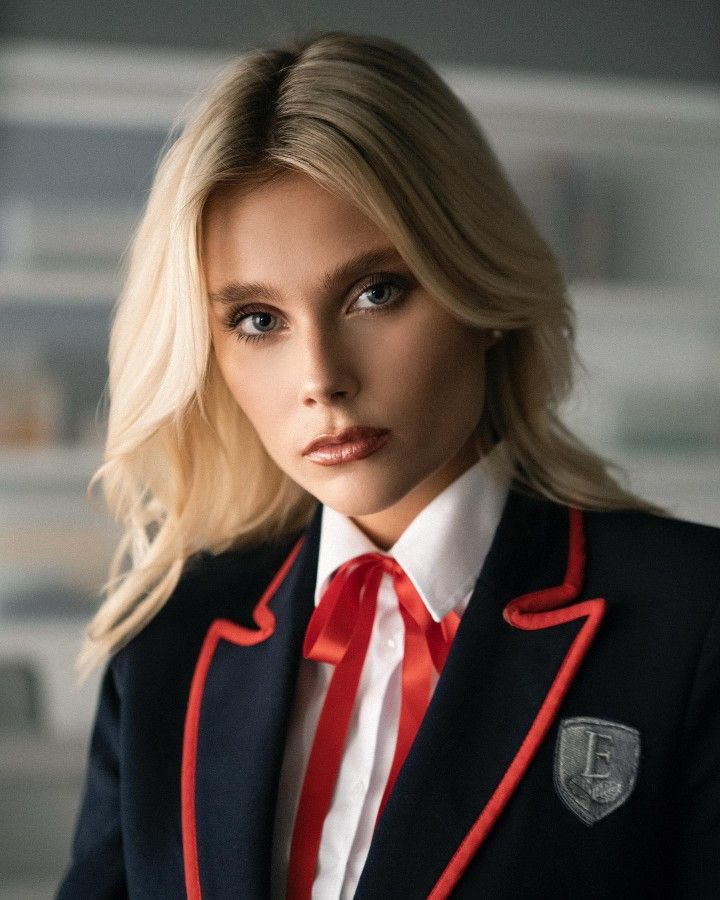 a woman in a suit and red tie is posing for a photo with her hands on her hips