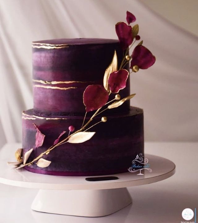 a three tiered cake with purple frosting and gold leaf decoration on top, sitting on a white plate