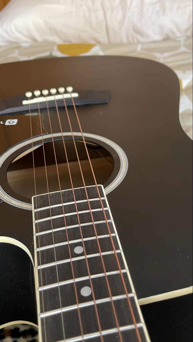 an acoustic guitar laying on a bed with its strings still attached to the fret