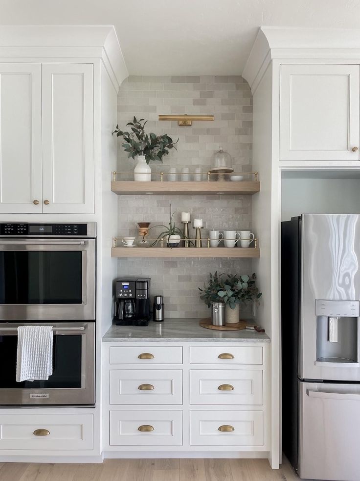 a kitchen with white cabinets and open shelving above the stove is shown in this image