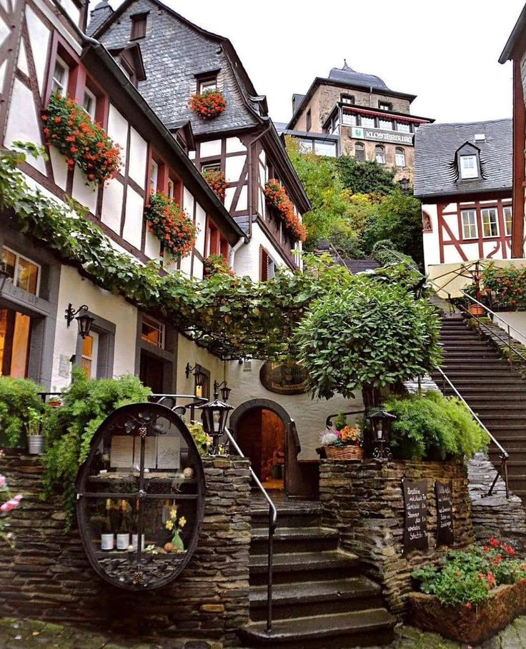 an old house with flowers growing on the windows and stairs leading up to it's entrance