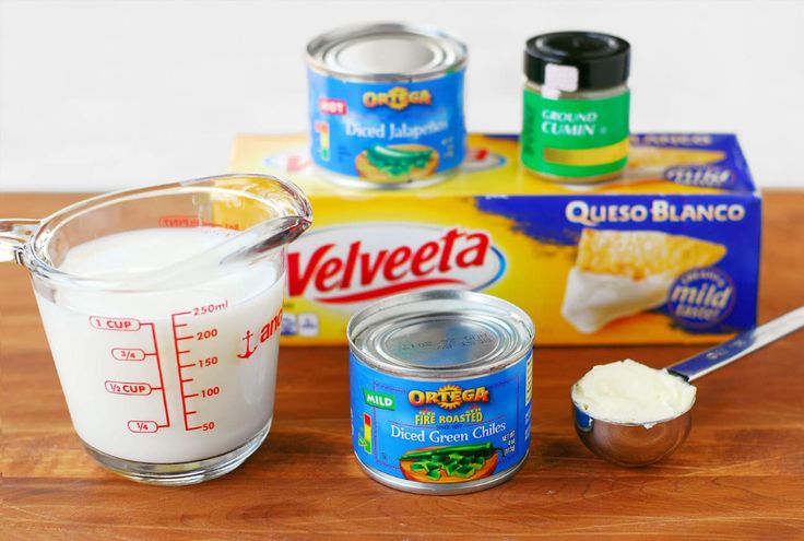 ingredients to make cheesecake sitting on top of a wooden table next to a measuring cup