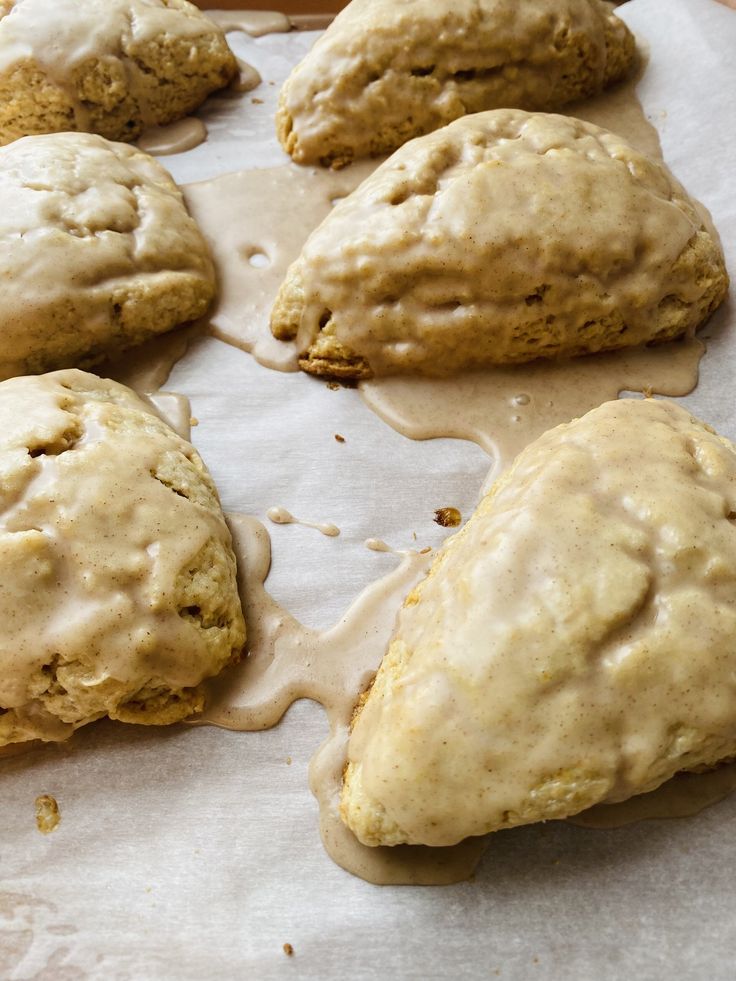 some biscuits are sitting on a piece of parchment paper and drizzled with icing