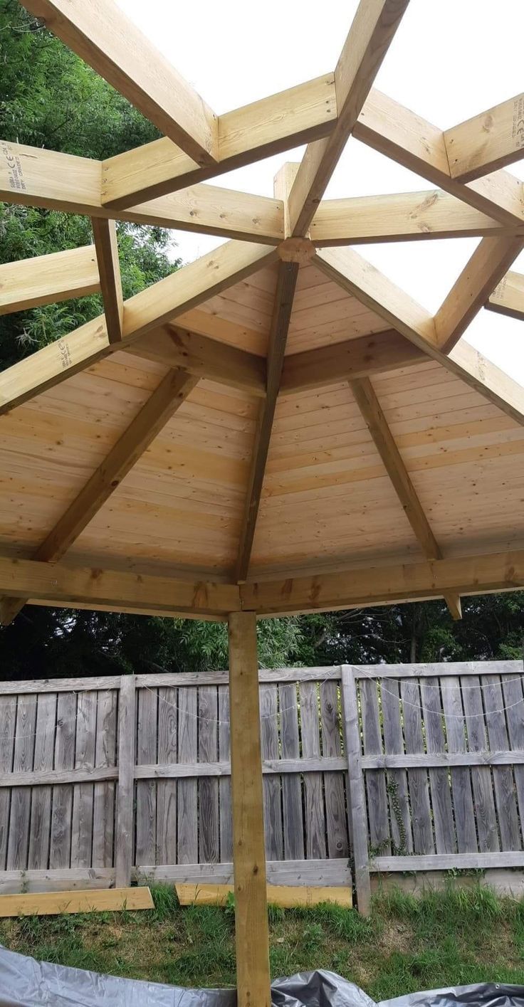 a wooden gazebo sitting on top of a lush green field