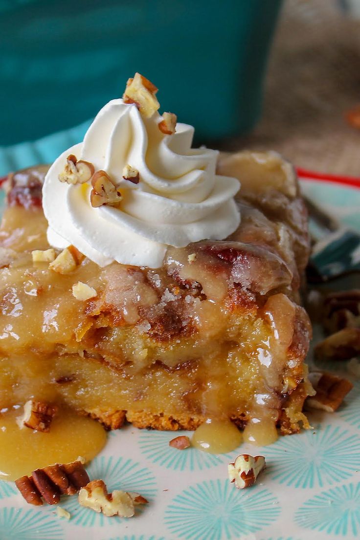 a piece of cake with whipped cream on top and pecans around the edges is sitting on a plate