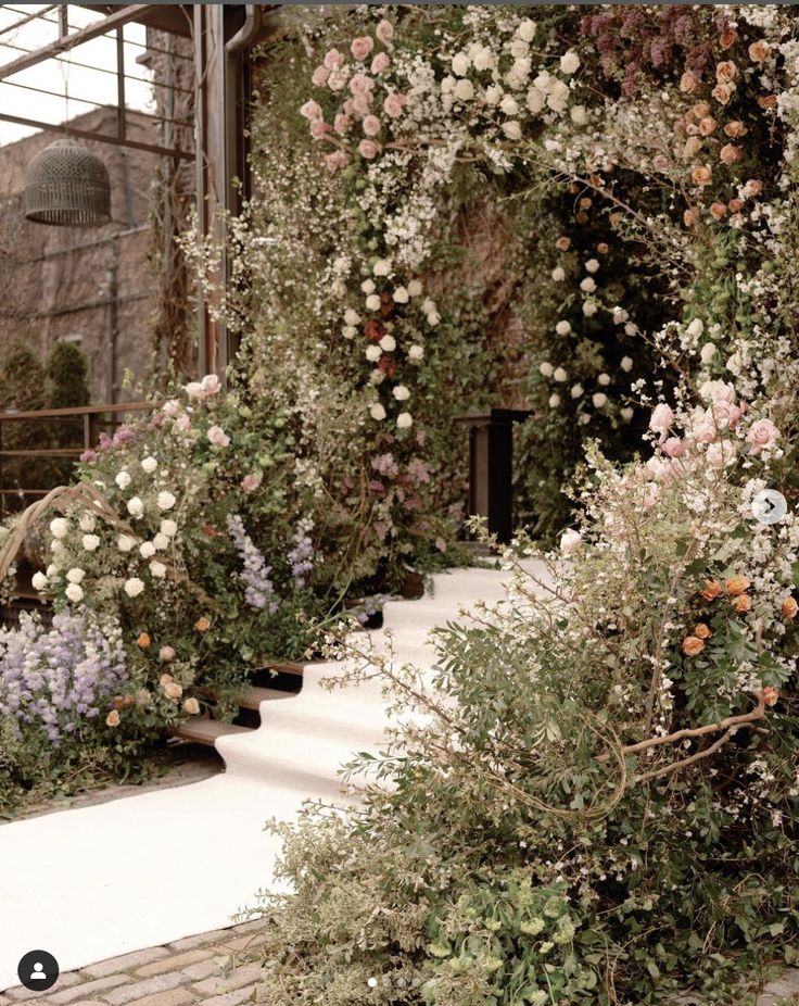 an outdoor area with flowers and plants growing on the walls, stairs leading up to it