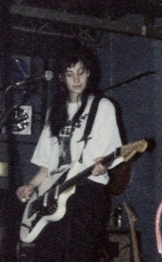 a man standing in front of a microphone while holding a guitar