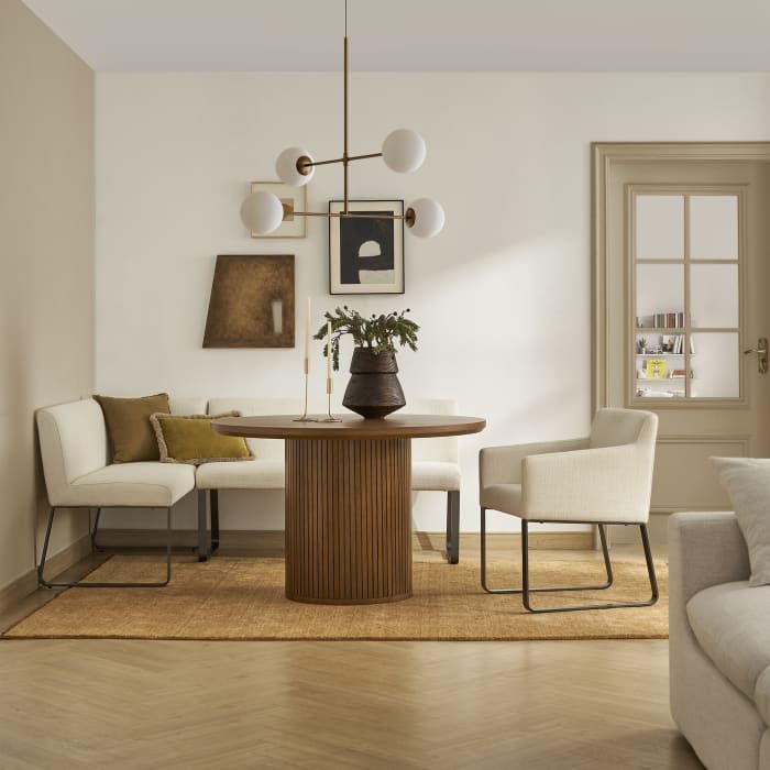 a living room with white furniture and wood flooring, including a table surrounded by chairs