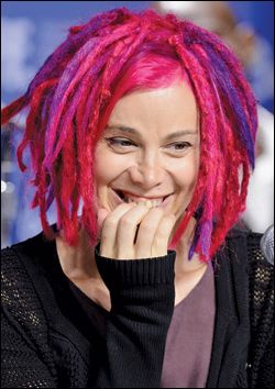 a woman with pink and purple dreadlocks sitting in front of a microphone