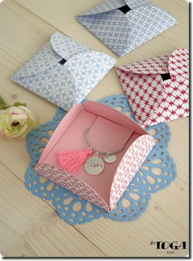 four different colored envelopes sitting on top of a doily next to a flower