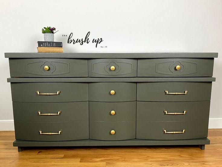 a green dresser with brass handles and knobs on it's drawers, against a white wall