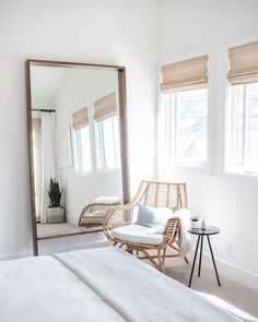 a bedroom with a large mirror and wicker chair in front of the bed,