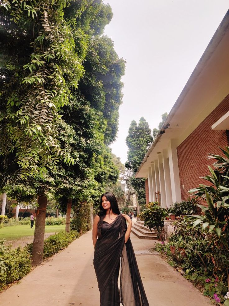 a woman in a black sari walking down a sidewalk