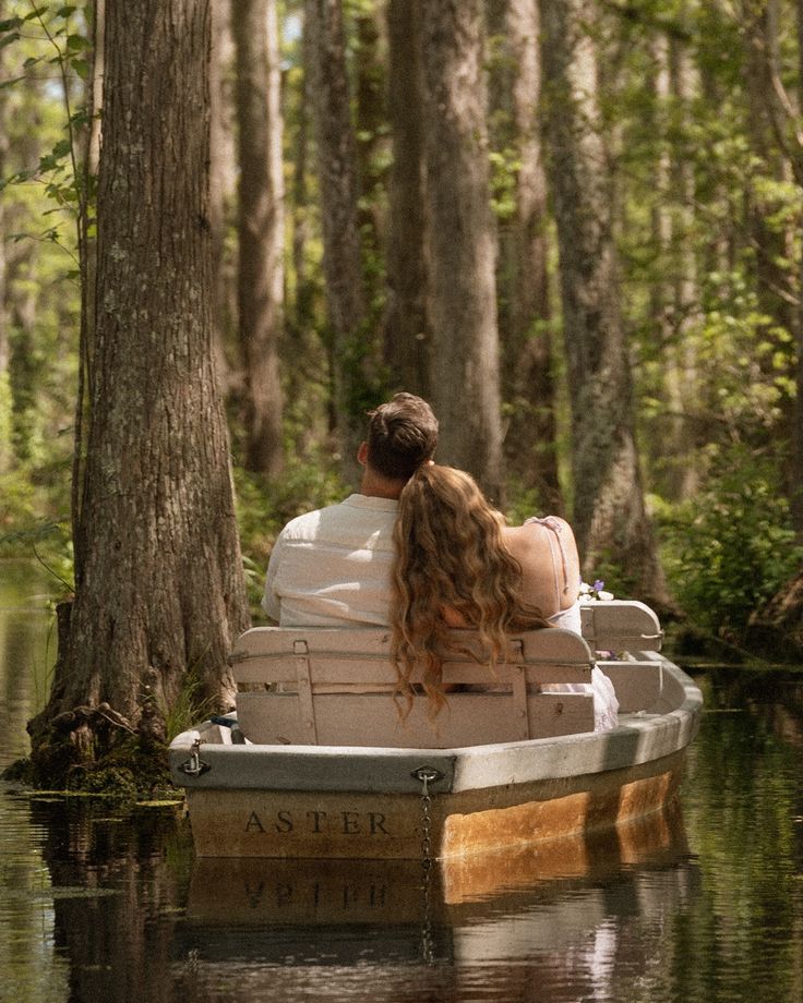 a man and woman are sitting on a boat in the middle of a swampy area