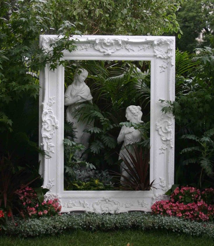 there is a white mirror in the middle of some flowers and plants on the ground