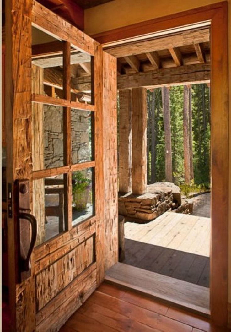 an open wooden door leading to a bedroom in a log cabin with stone walls and wood flooring