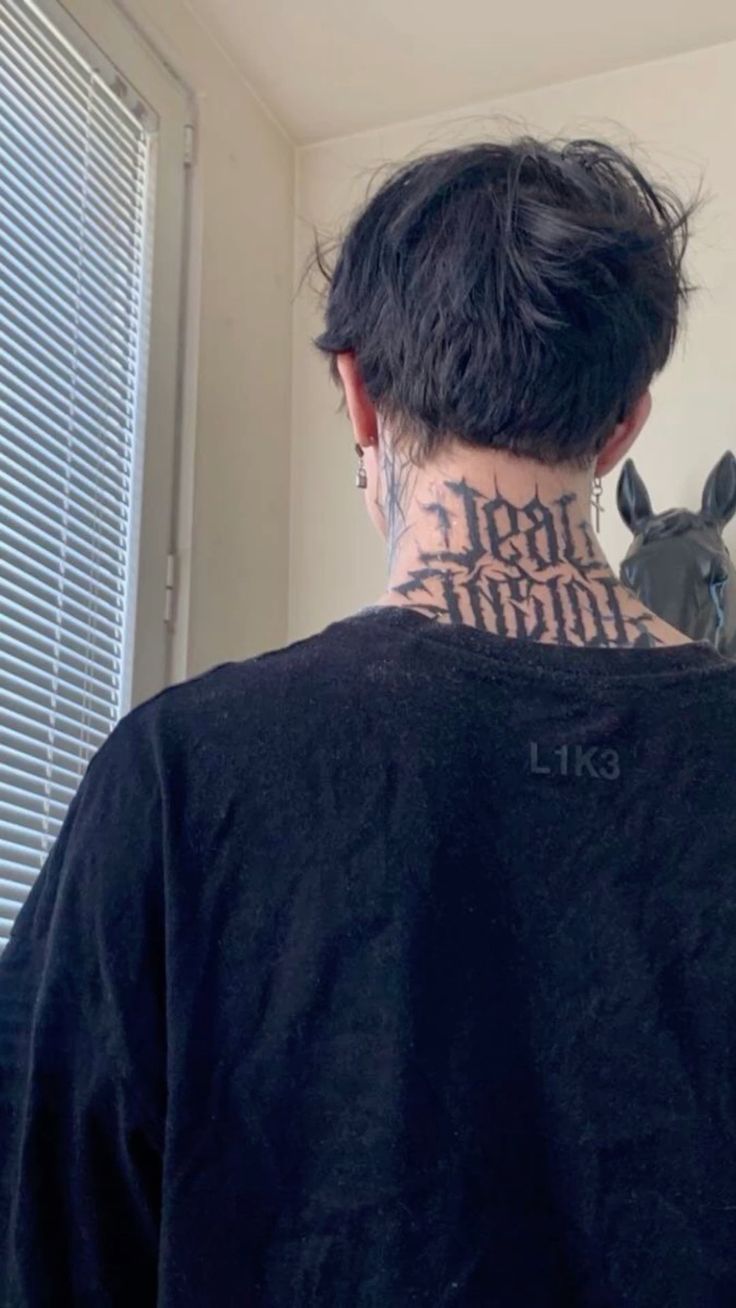 the back of a man's neck with tattoos on it