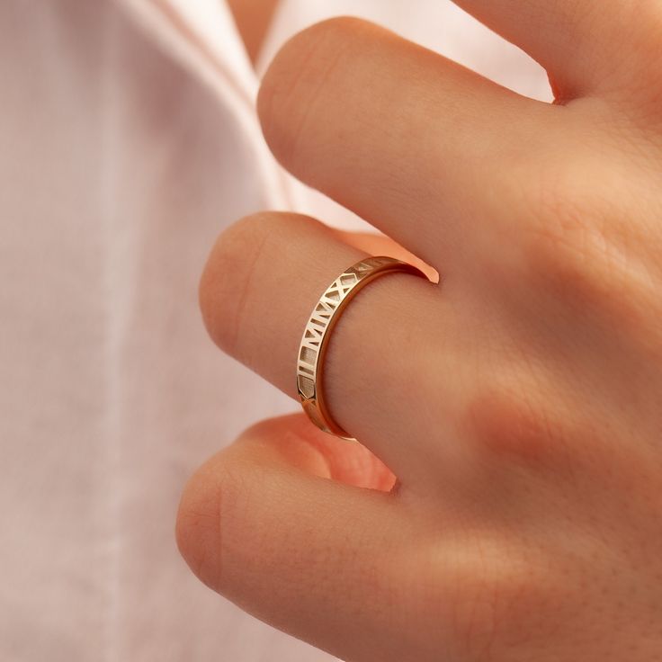 a woman's hand wearing a gold ring with the word love written on it