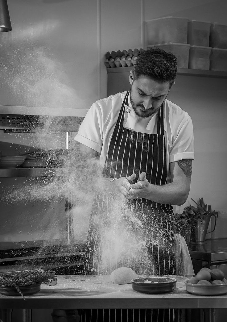 a man in an apron is sprinkling flour on the counter