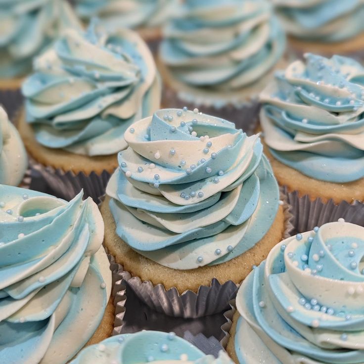 cupcakes with blue frosting and white icing are arranged on top of each other