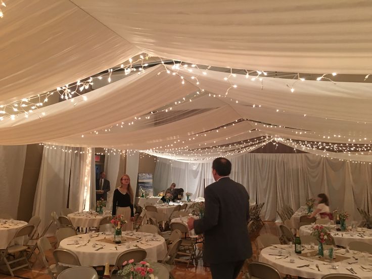 a man and woman standing in front of a white tent with tables set up for an event