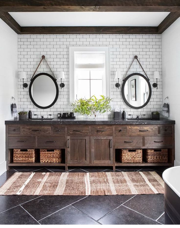 a bathroom with two sinks, mirrors and a rug in front of the bathtub