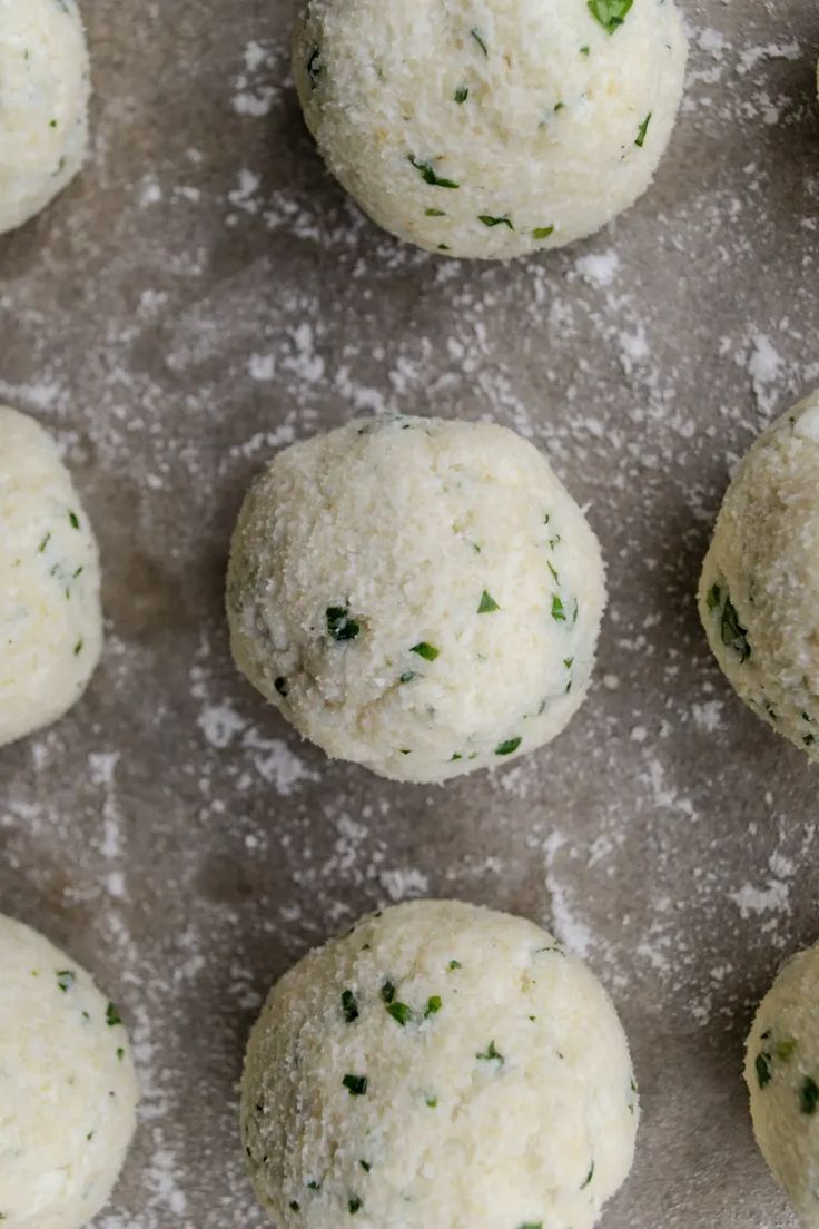 several balls of food sitting on top of a baking pan covered in cheese and herbs