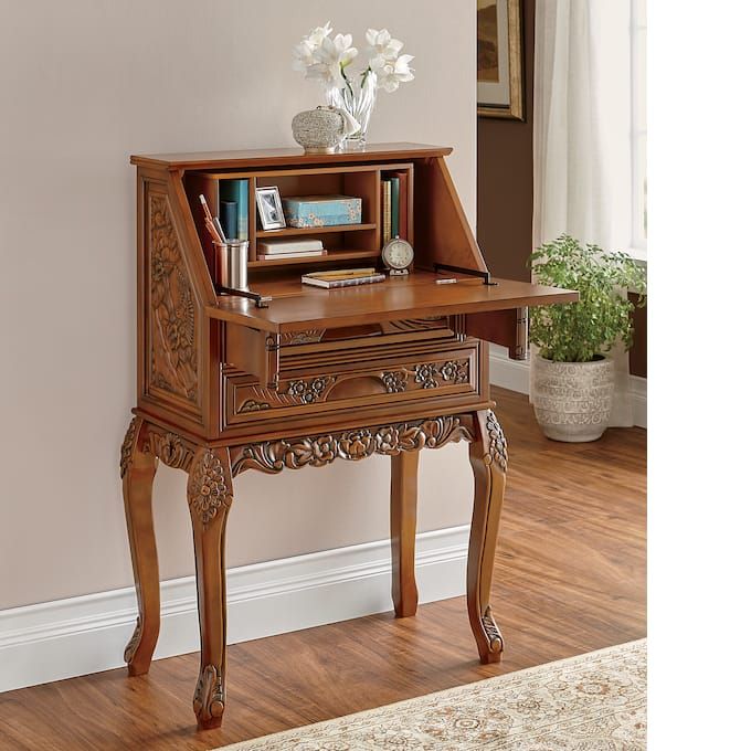 a wooden desk with an open book shelf on it's side and flowers in vase next to it