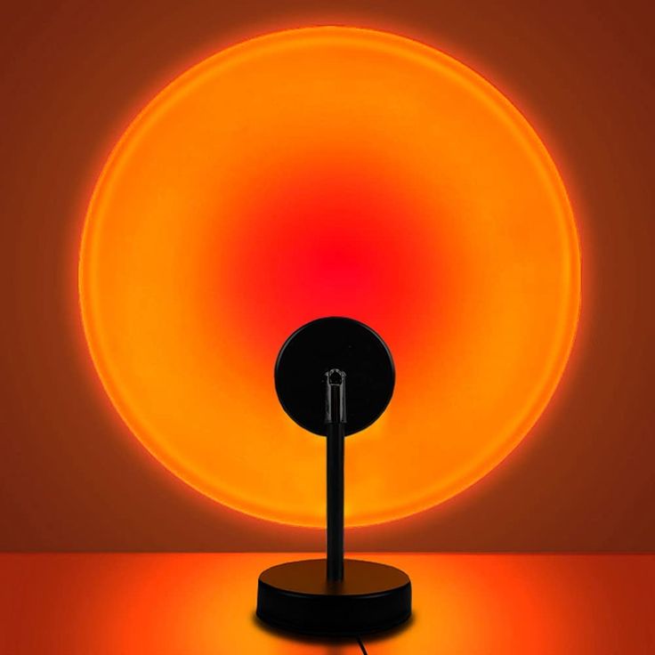 an orange and red light is shining in the dark room with a black lamp on it