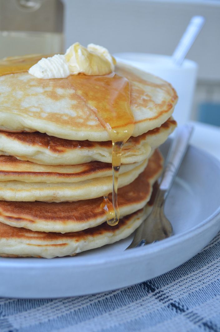 a stack of pancakes on a plate with syrup being drizzled over them