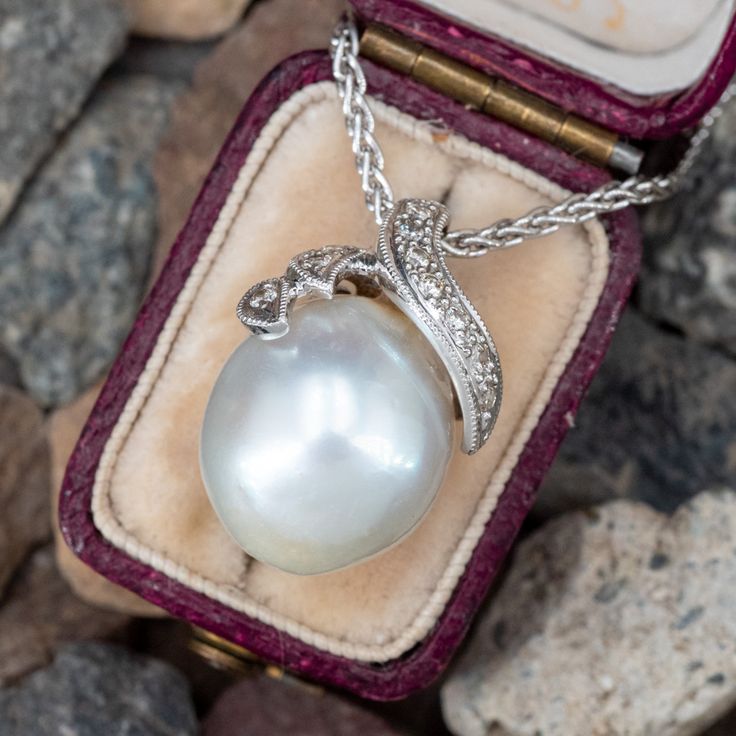 This fabulous pearl necklace features an 18k white gold pendant accented with one (1), post set, cultured South Sea pearl. The bail is accented with ten (10), bead set, round brilliant cut diamonds, bordered with milgrain edging. The pendant measures 20.6mm X 14.2mm. The pendant is suspended from a 14k white gold neck chain measuring 1.6mm wide and an overall length of 16 inches. Formal Pear-shaped Diamond Pearl Necklace, Formal Pearl Pendant Jewelry In Pear Shape, Pearl Pendant Jewelry In Pear Shape For Formal Events, Exquisite Pearl Necklace With Diamond Accents For Formal Events, Formal Fine Jewelry Pearl Necklace With Diamond Accents, Formal Pearl Necklace With Diamond Accents, Anniversary White Gold Pearl Necklace With Diamond Accents, Heirloom Diamond Jewelry Pear Shaped, Formal Pear-shaped Pearl Pendant Necklace