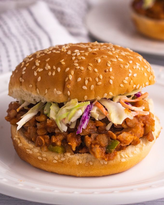 a pulled pork sandwich with coleslaw and slaw on a white bread bun