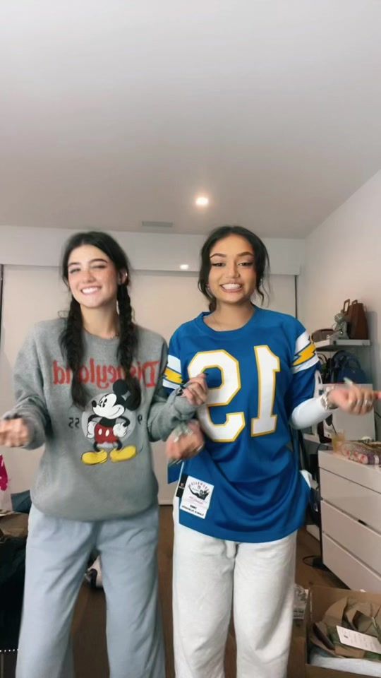 two young women standing next to each other in front of a dresser and television screen