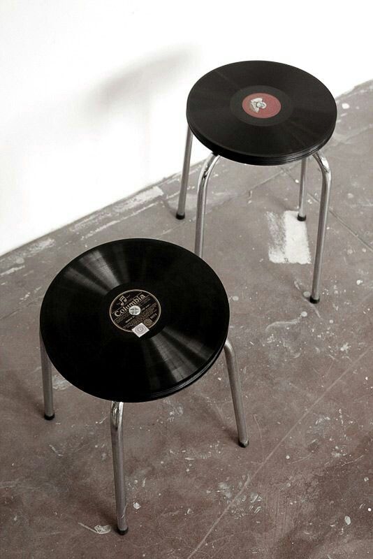 two small black tables sitting next to each other on top of a cement floor in front of a white wall