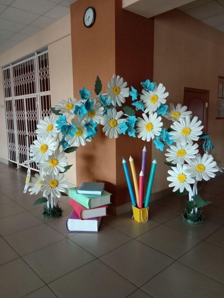 some books and pencils are sitting on the floor next to flowers in vases