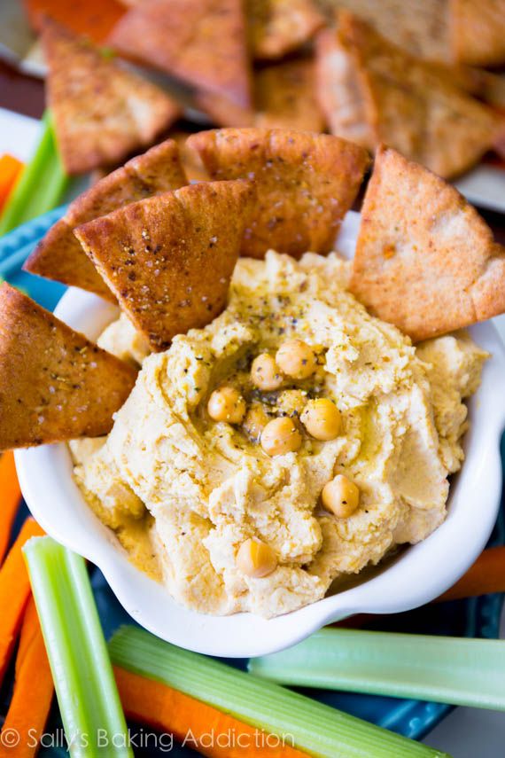 hummus and crackers in a bowl with celery sticks on the side