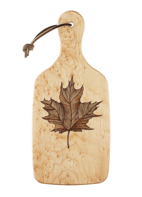 a wooden cutting board with a maple leaf on it